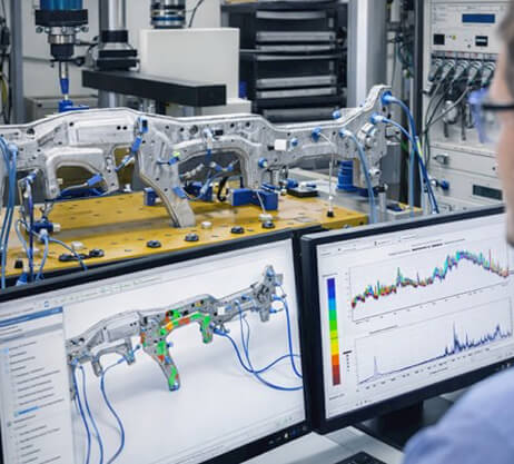 Engineering lab with structural castings on test fixtures and data on screen